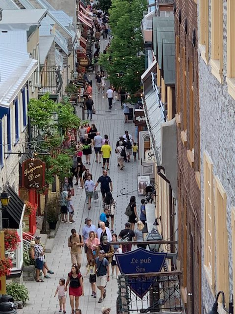Blick durch eine historische Gasse in Québec auf das Straßenleben
