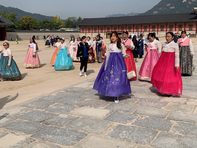 Besucher in bunten traditionellen Hanbok-Kleidern im Innenhof des Gyeongbokgung-Palastes